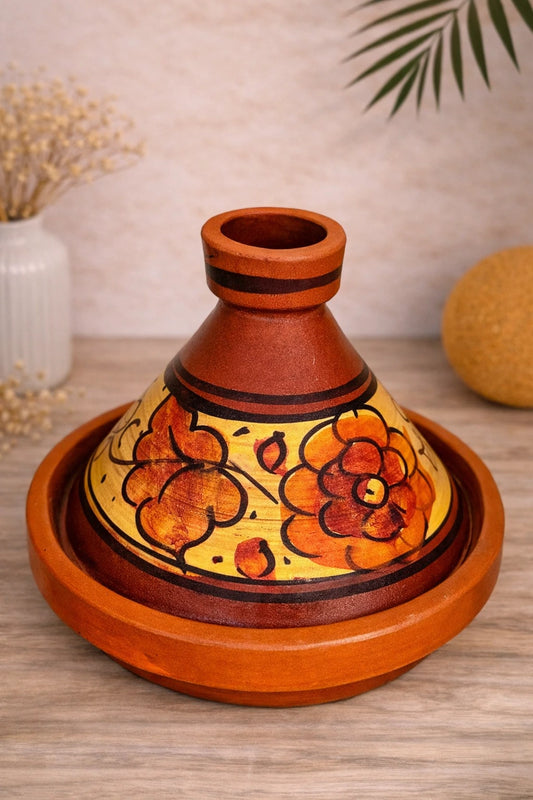 Vue du dessus d’un tajine en poterie artisanale marocaine aux motifs floraux jaunes et ocres